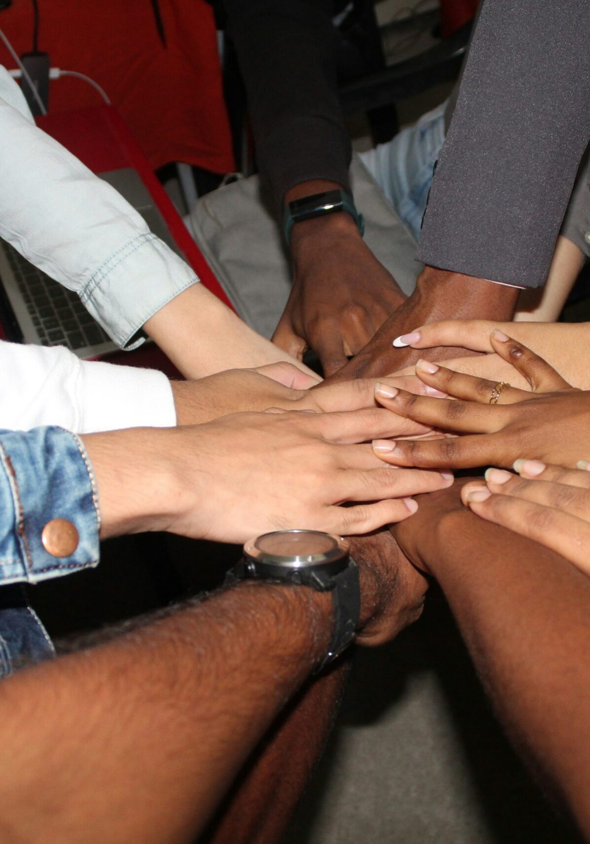 rineshkumar-ghirao-UdDjFekHQuk-unsplash decorative image: a team of people with their hands in